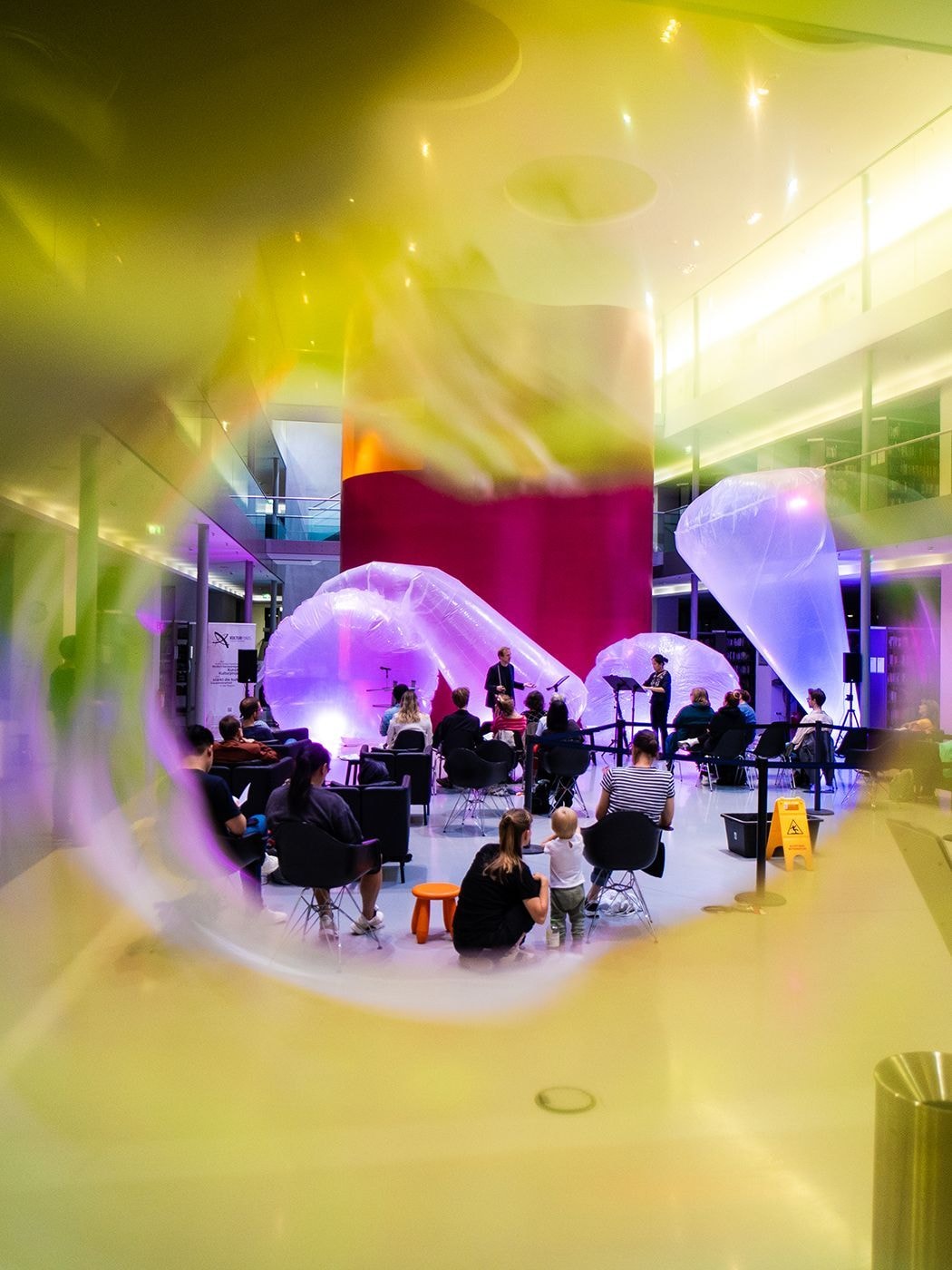 Ein verschwommener gelber Rand kreiert einen runden Bildausschnitt, in dem Publikum und Musizierende zu sehen sind.