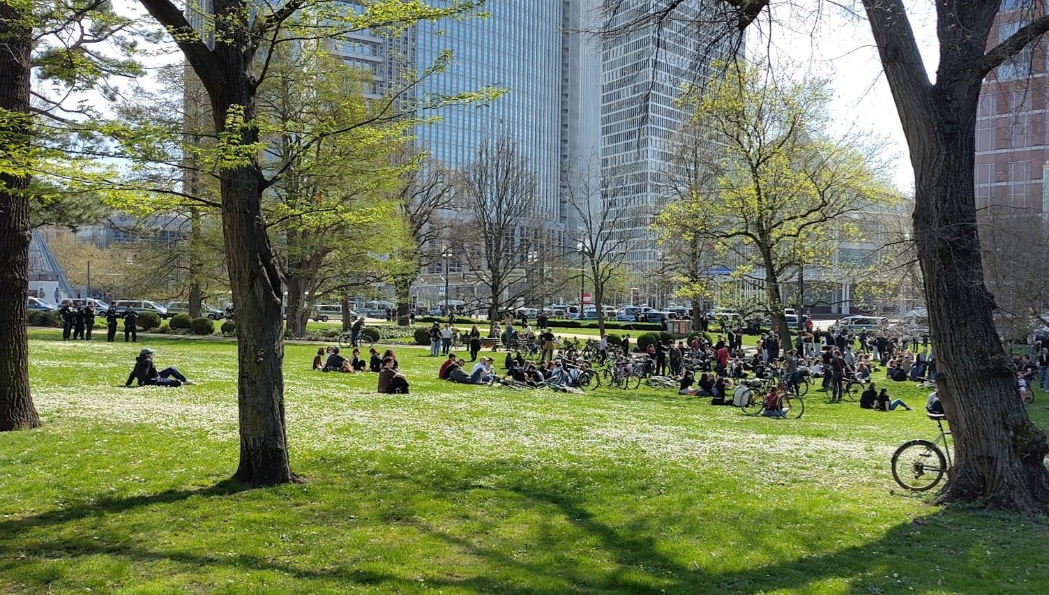 Menschen sitzten auf einer grünen Wiese inmitten der Stadt und genießen die Sonne