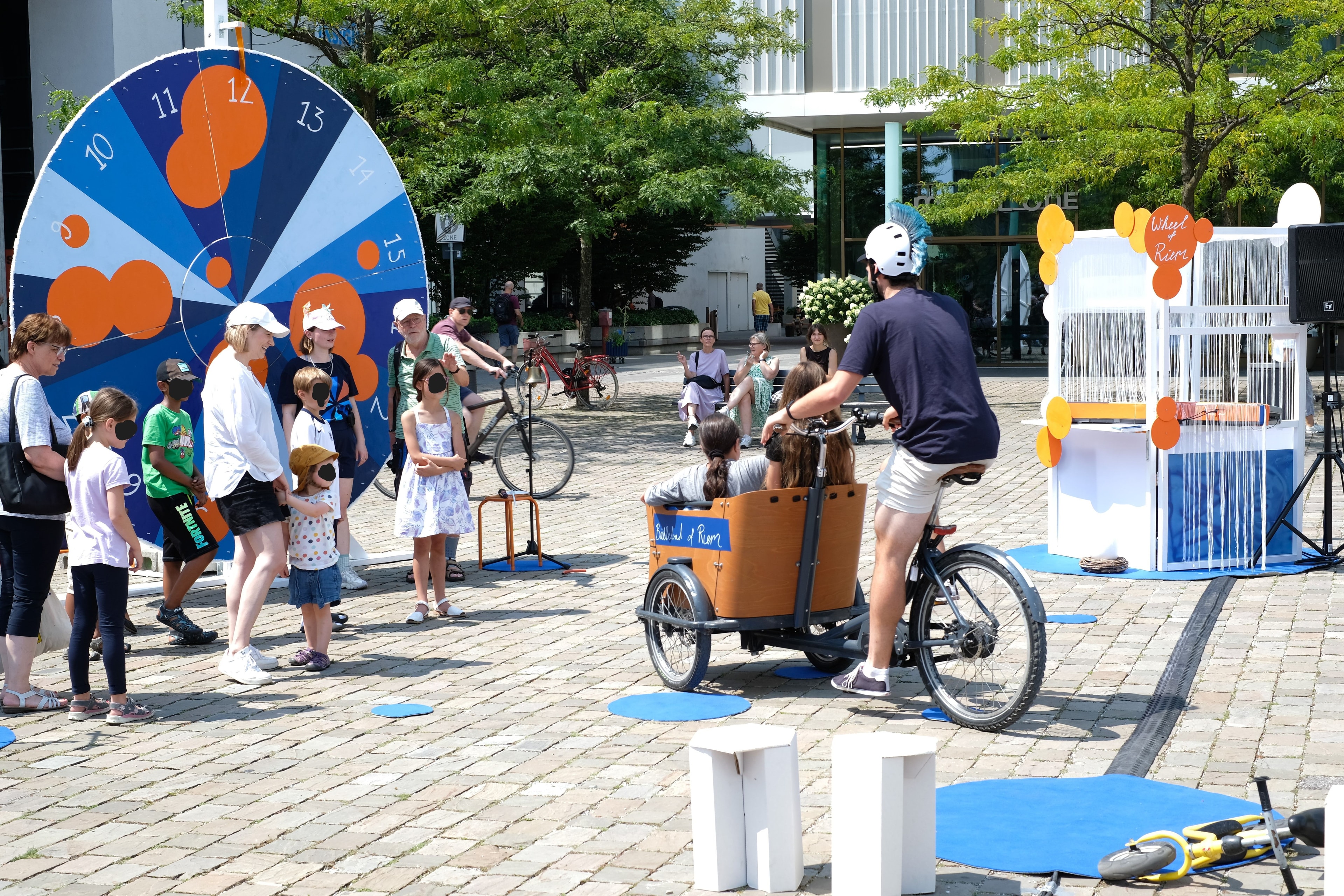 Kinder stehen auf einem Platz mit unterschiedlichen Fahrzeugen mit Rädern