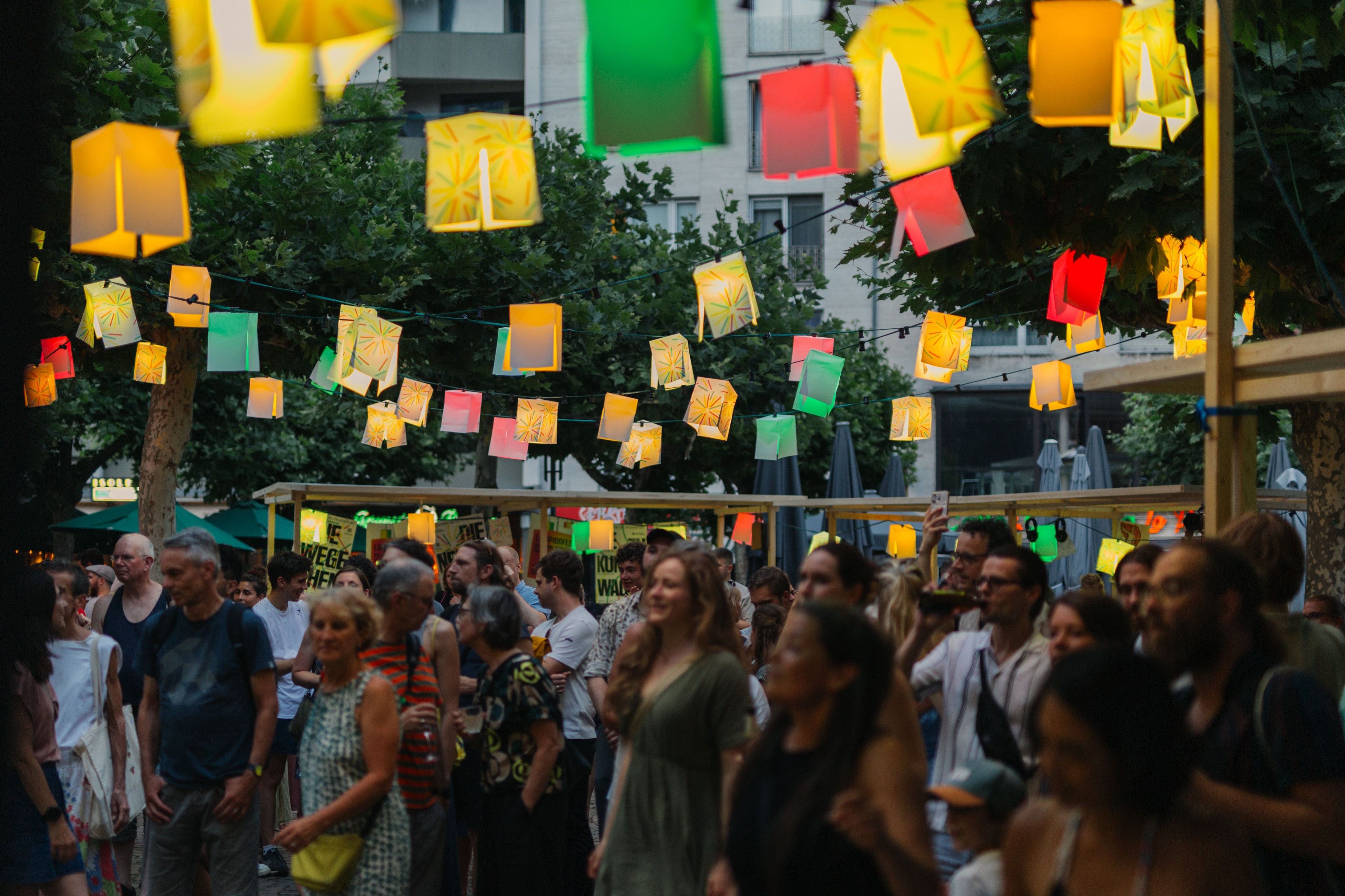Heiter gelaunte Menschen unter beleuchteten Lampion-Girlanden