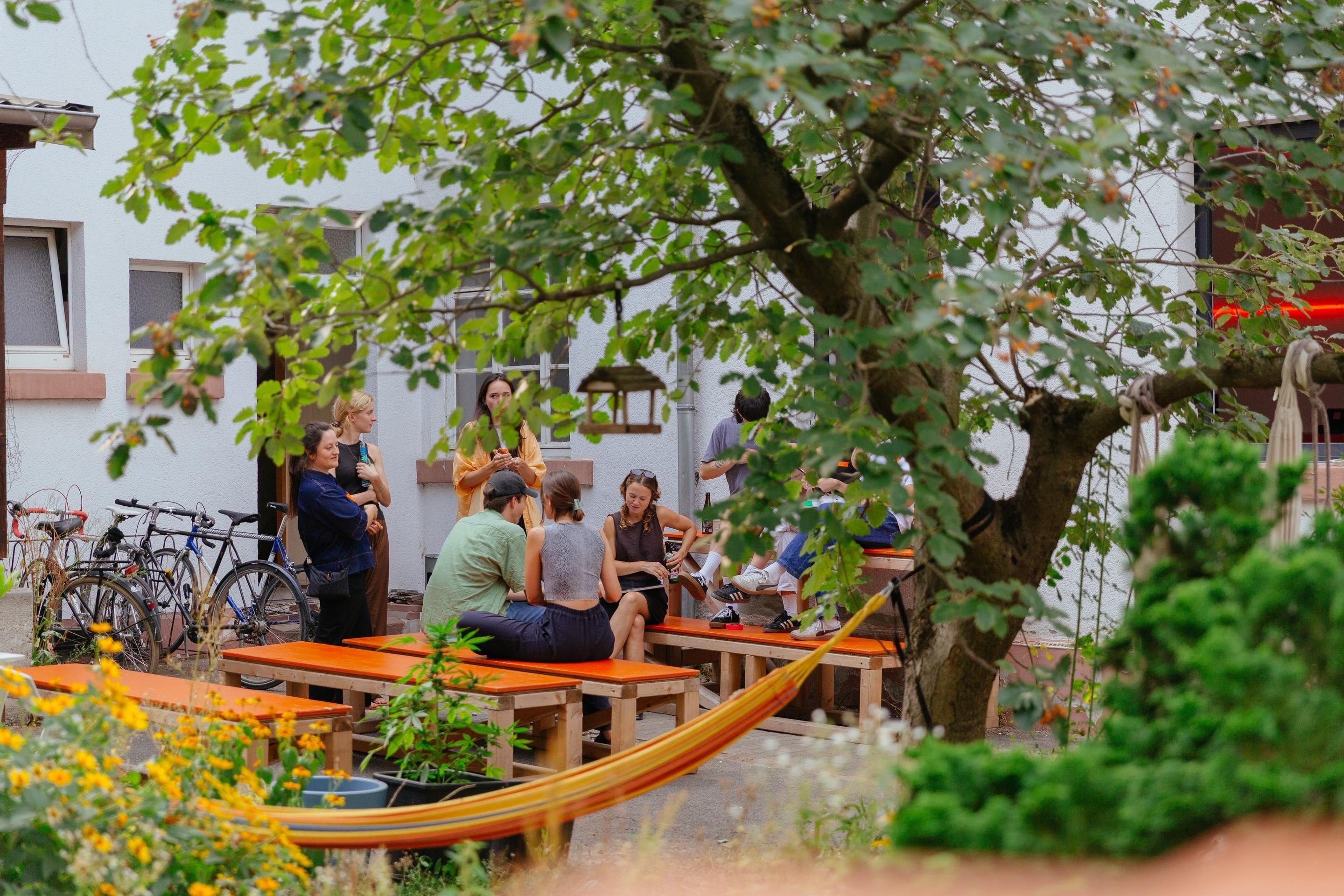 Junge Menschen sitzen gemeinsam in einem grünen Innenhof
