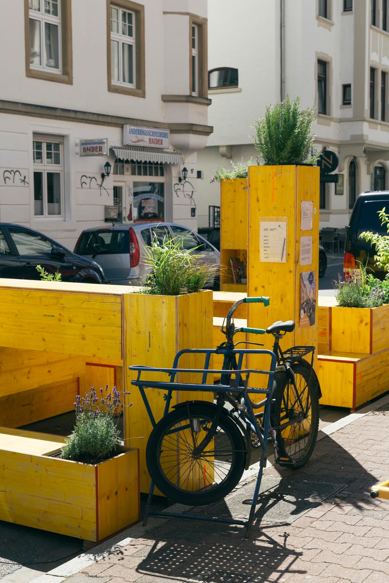 Ein Fahrrad steht vor gelben Sitzmöbeln in der Straße. 