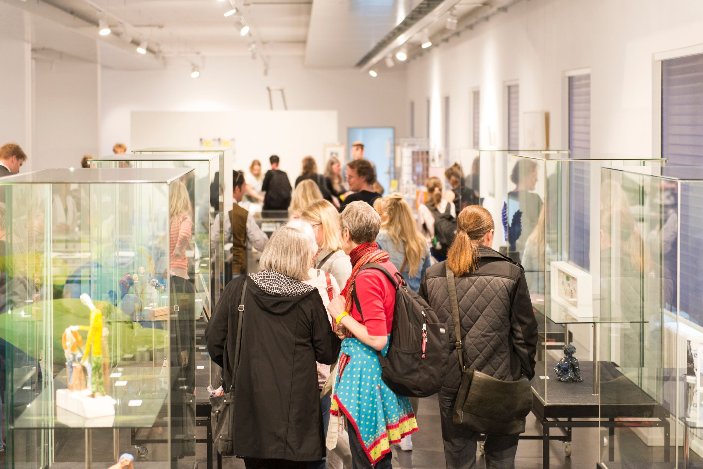 Menschen stehen in einer Galerie vor Exponaten