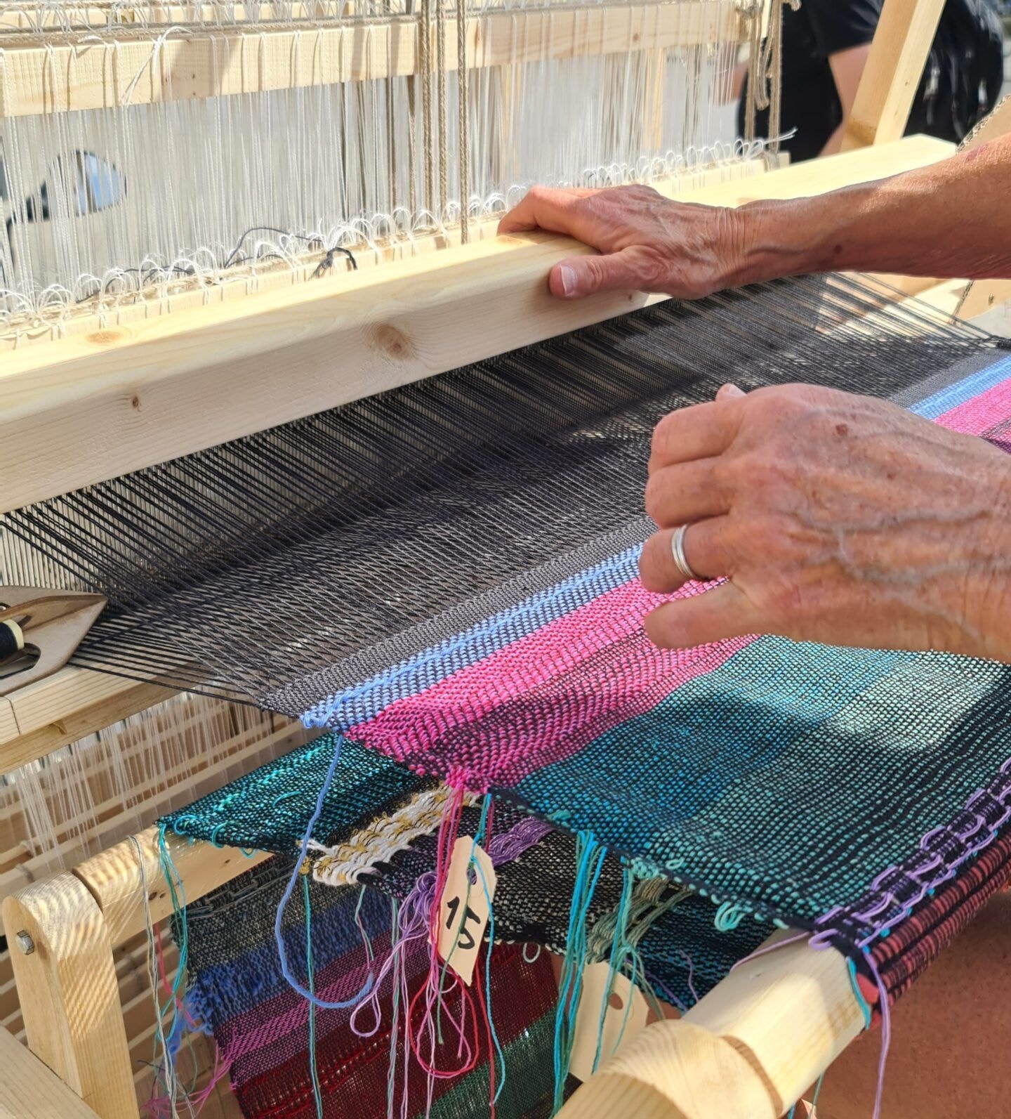 Hände arbeiten an einem mobilen Webstuhl
