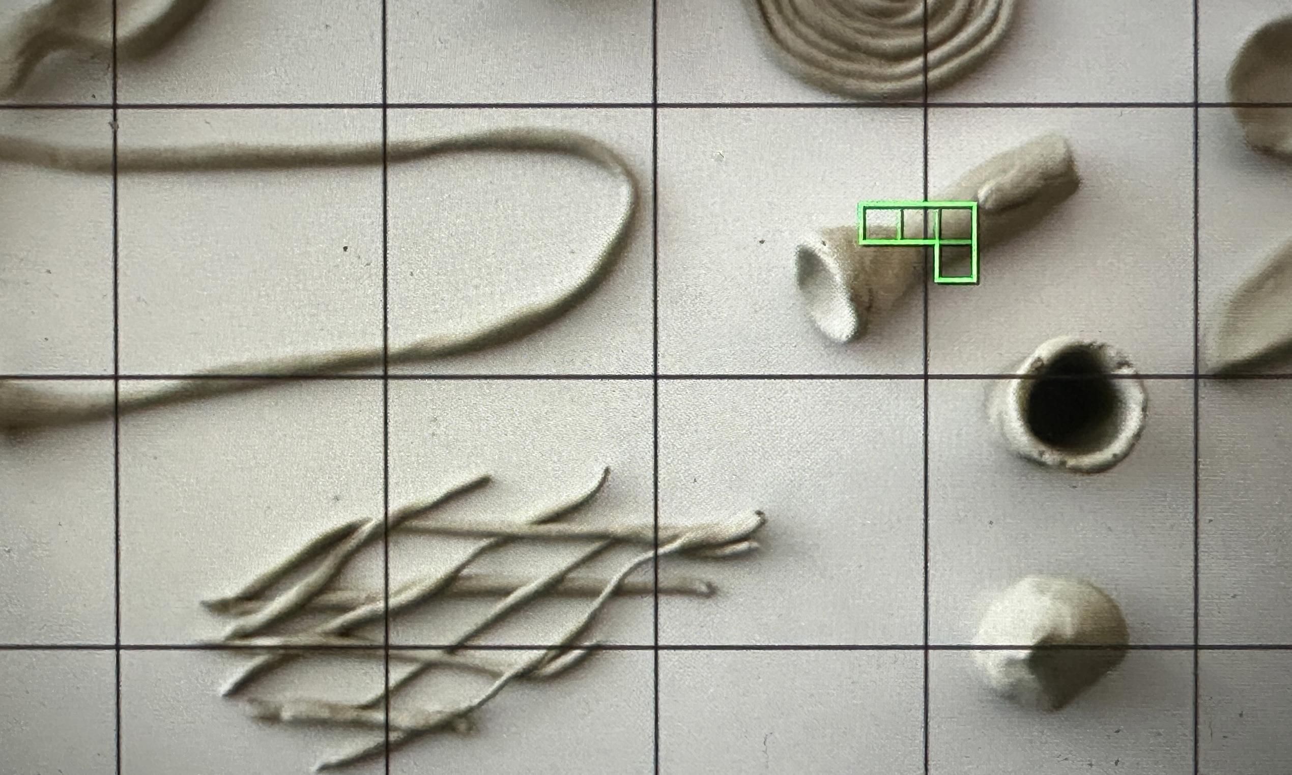 Gegenstände auf einem weißen Tisch. Davor ein quadratisches Raster.