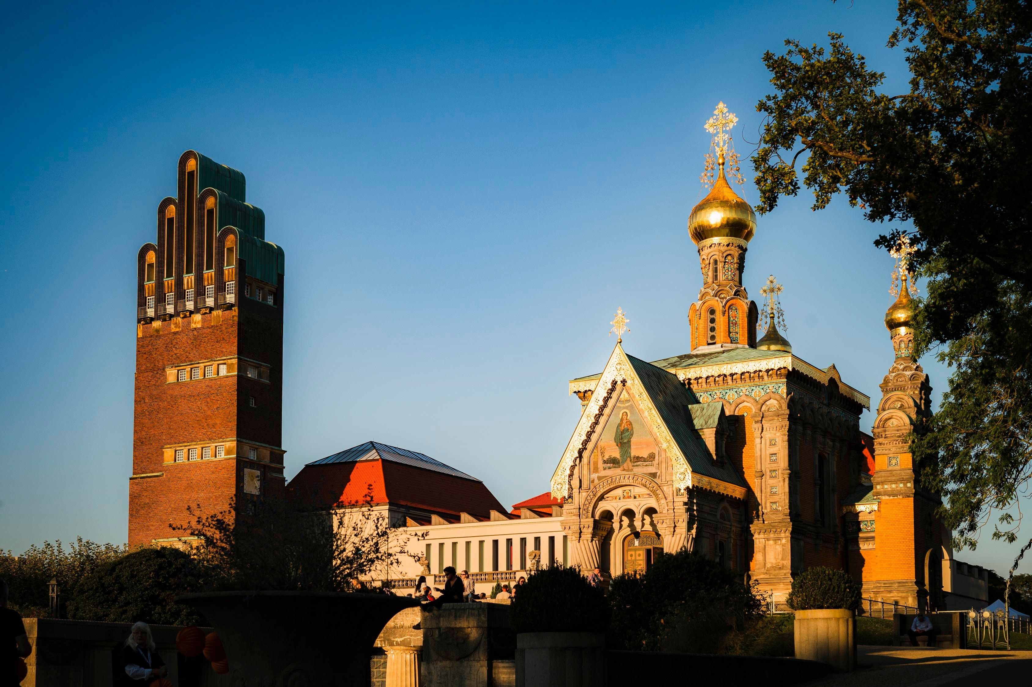 Die Mathildenhöhe ist im Sonnenuntergang vor blauem Himmel.