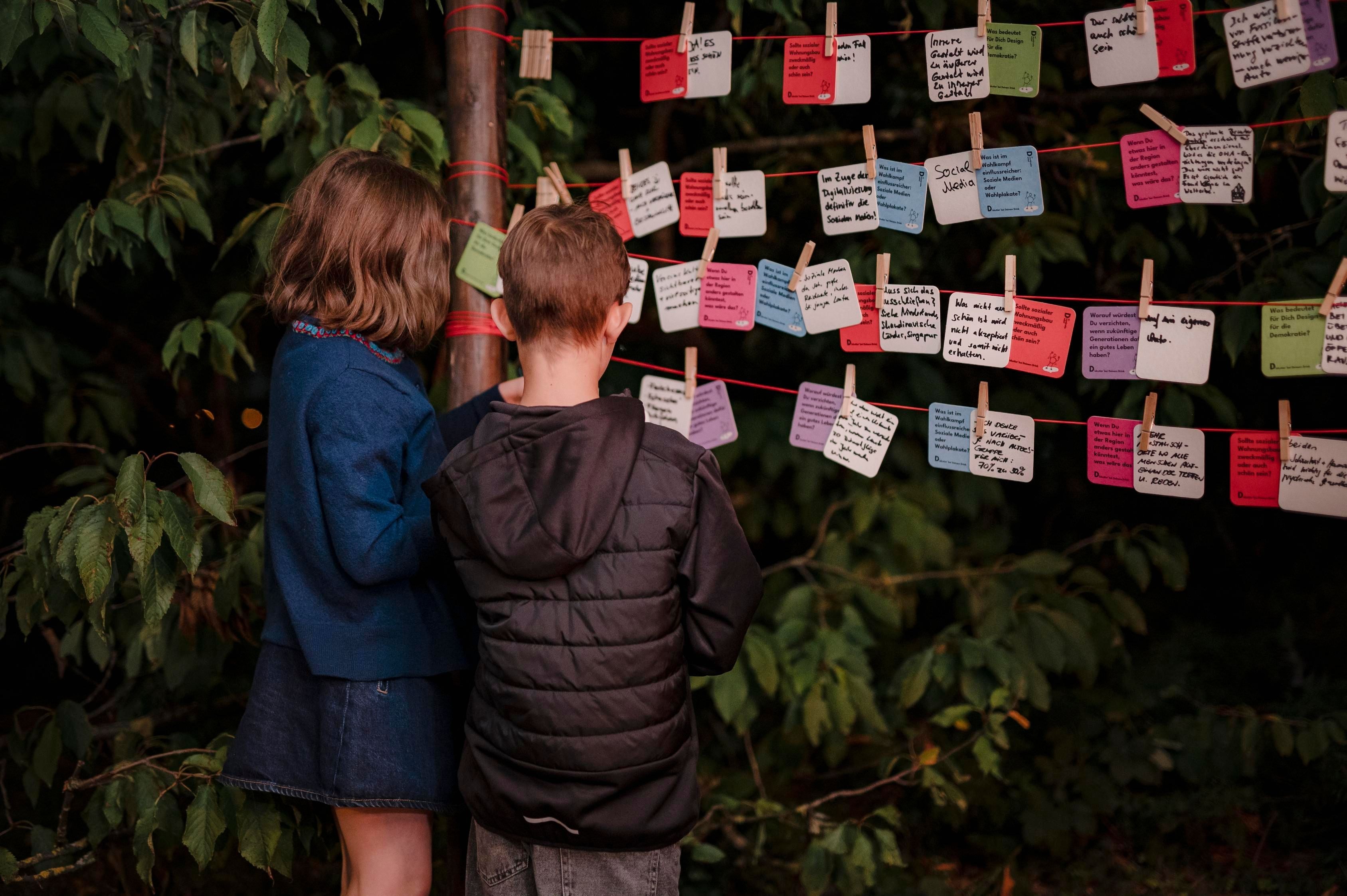 Kinder stehen vor mehreren beschrifteten Bierdeckeln.