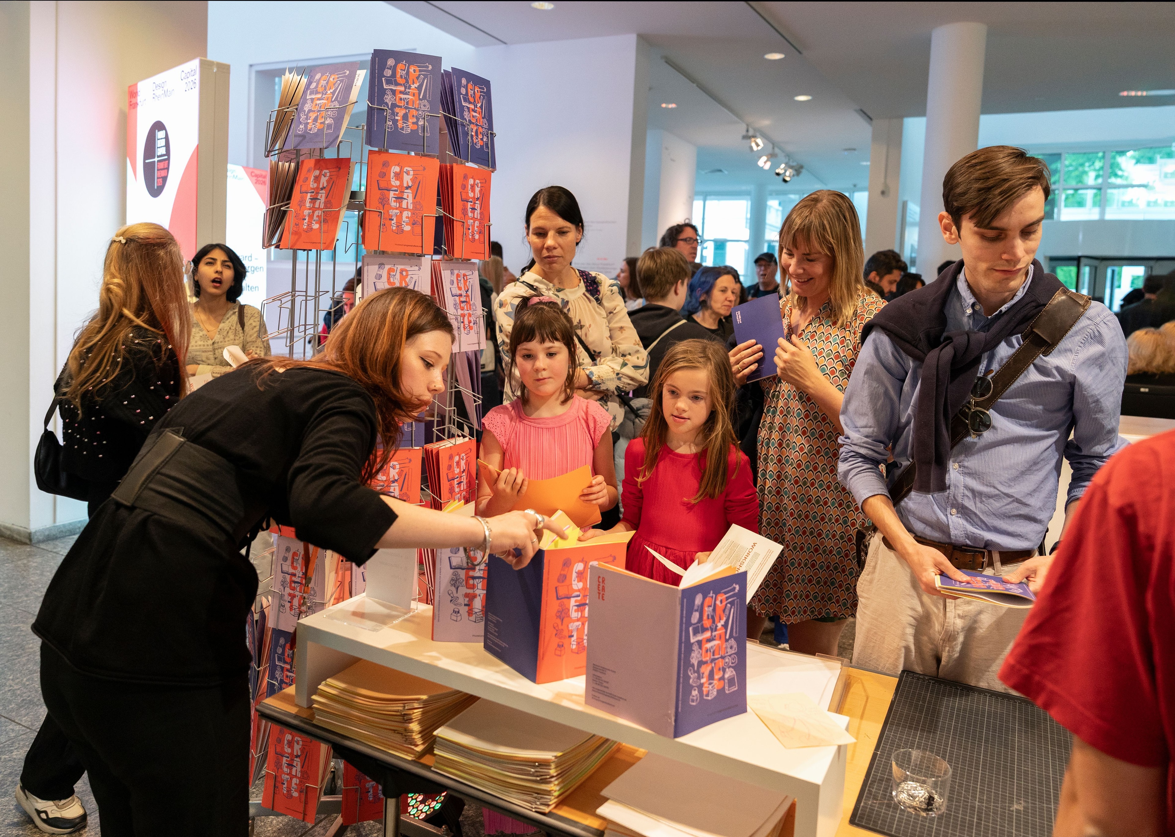 Eine junge Frau, die interessierten Kindern ein Heft erklärt