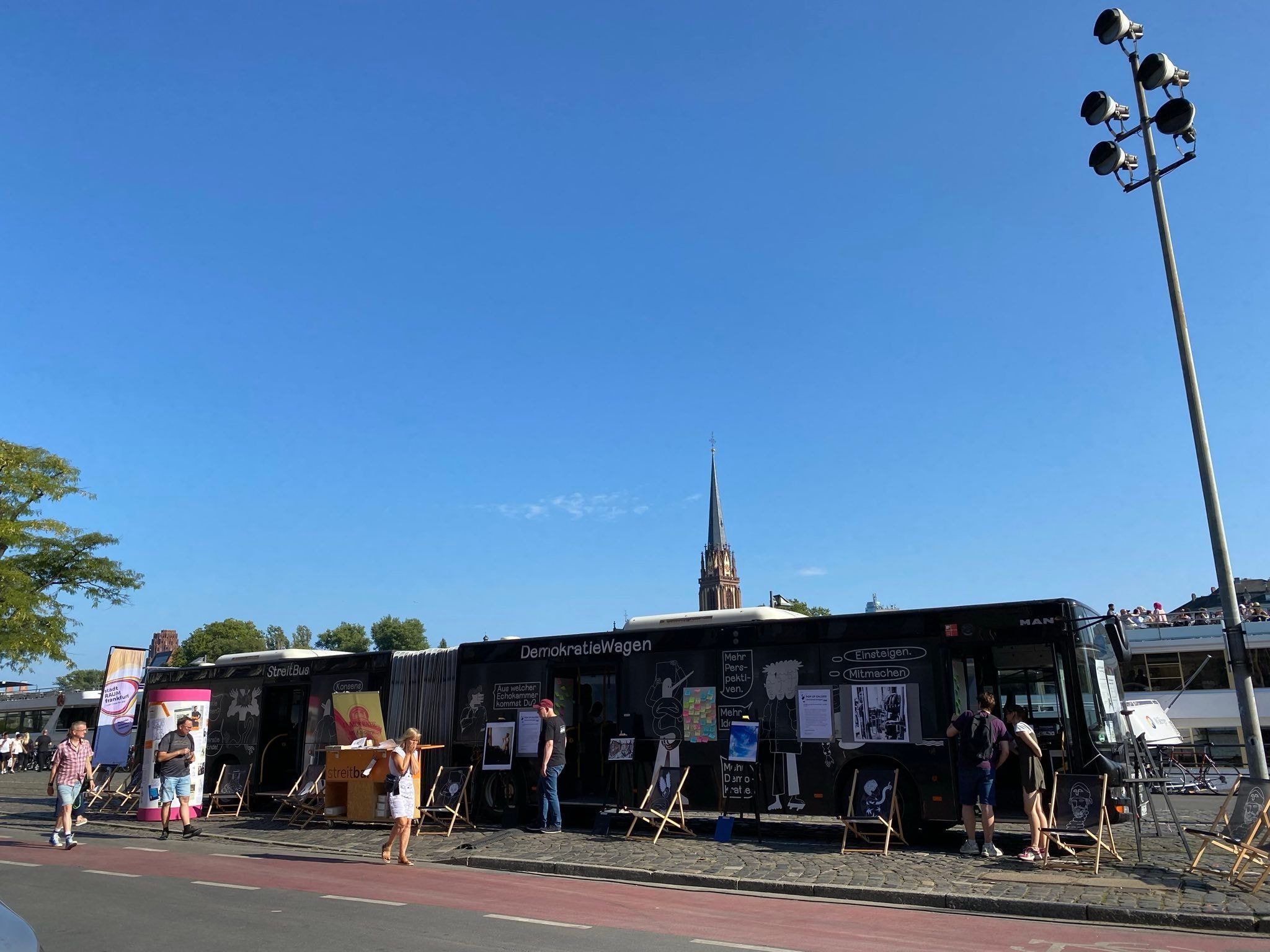 Ein mit Postern und Zeichnungen verzierter Bus: Der DemokratieWagen steht am Straßenrand.