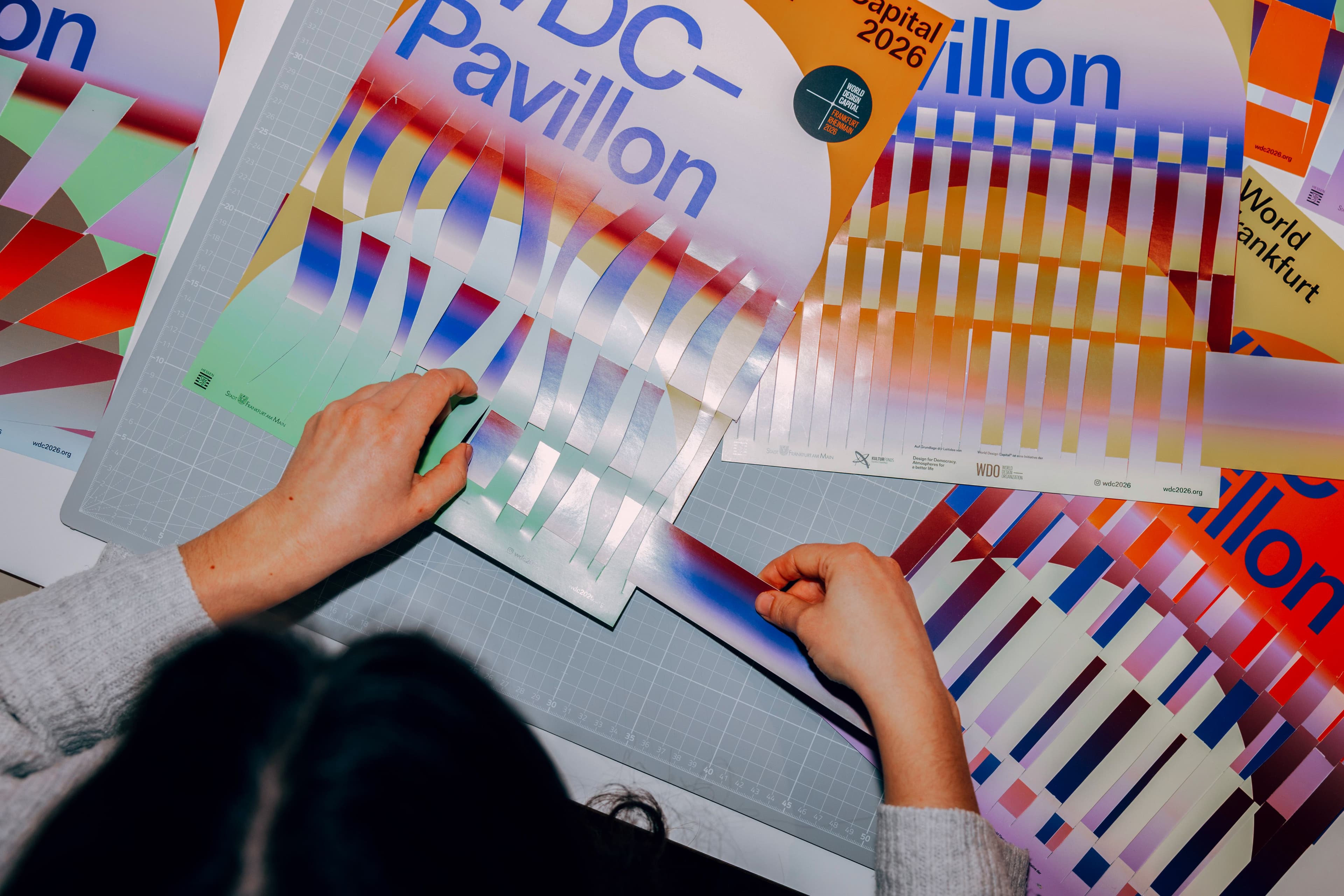 Eine Person bearbeitet Plakate vom WDC-Pavillon.