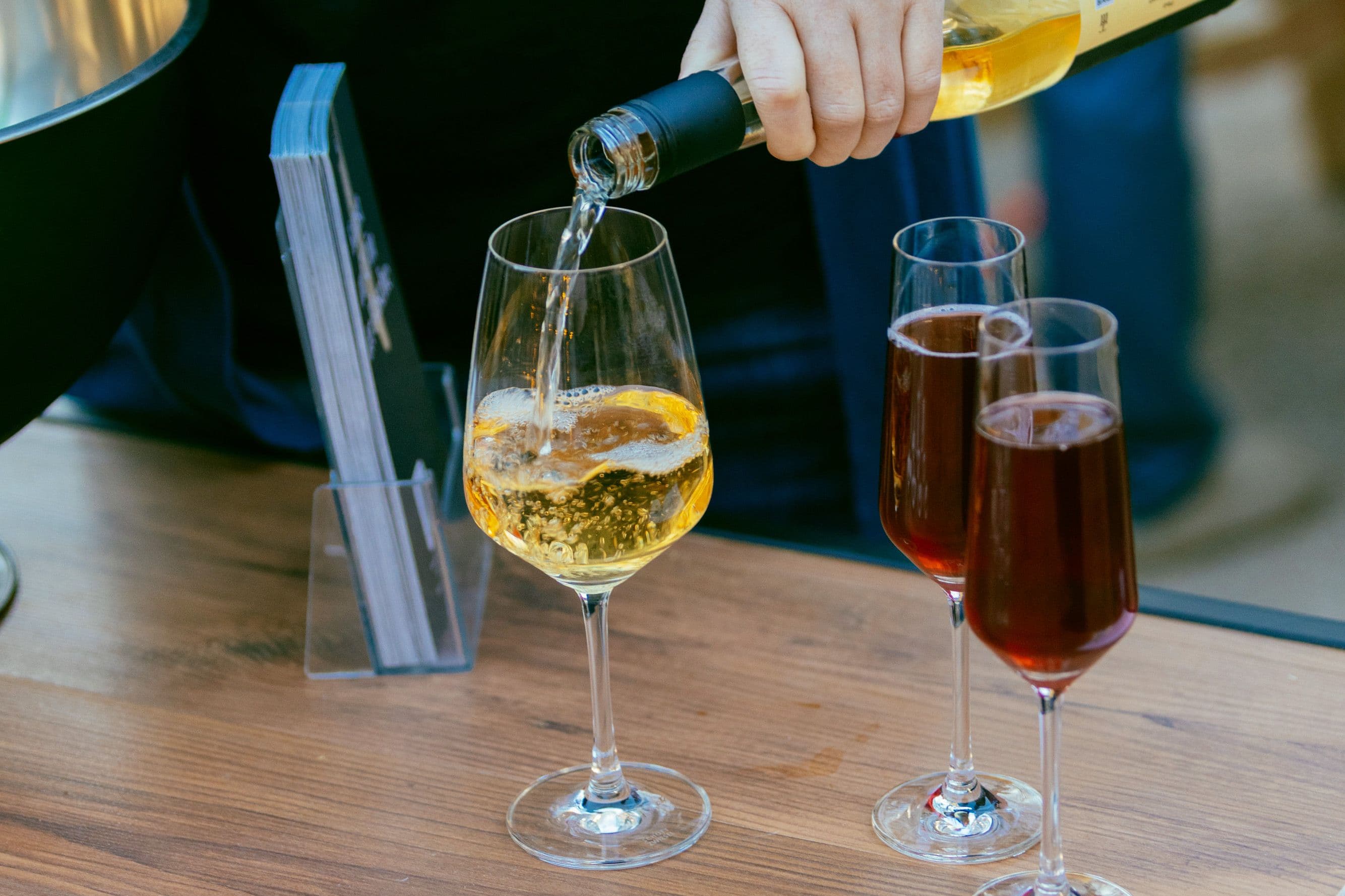 Eine Hand schenkt ein Glas Weißwein ein