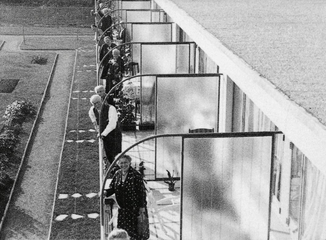 Schwarz-Weiß Foto von Menschen auf mehreren Balkonen