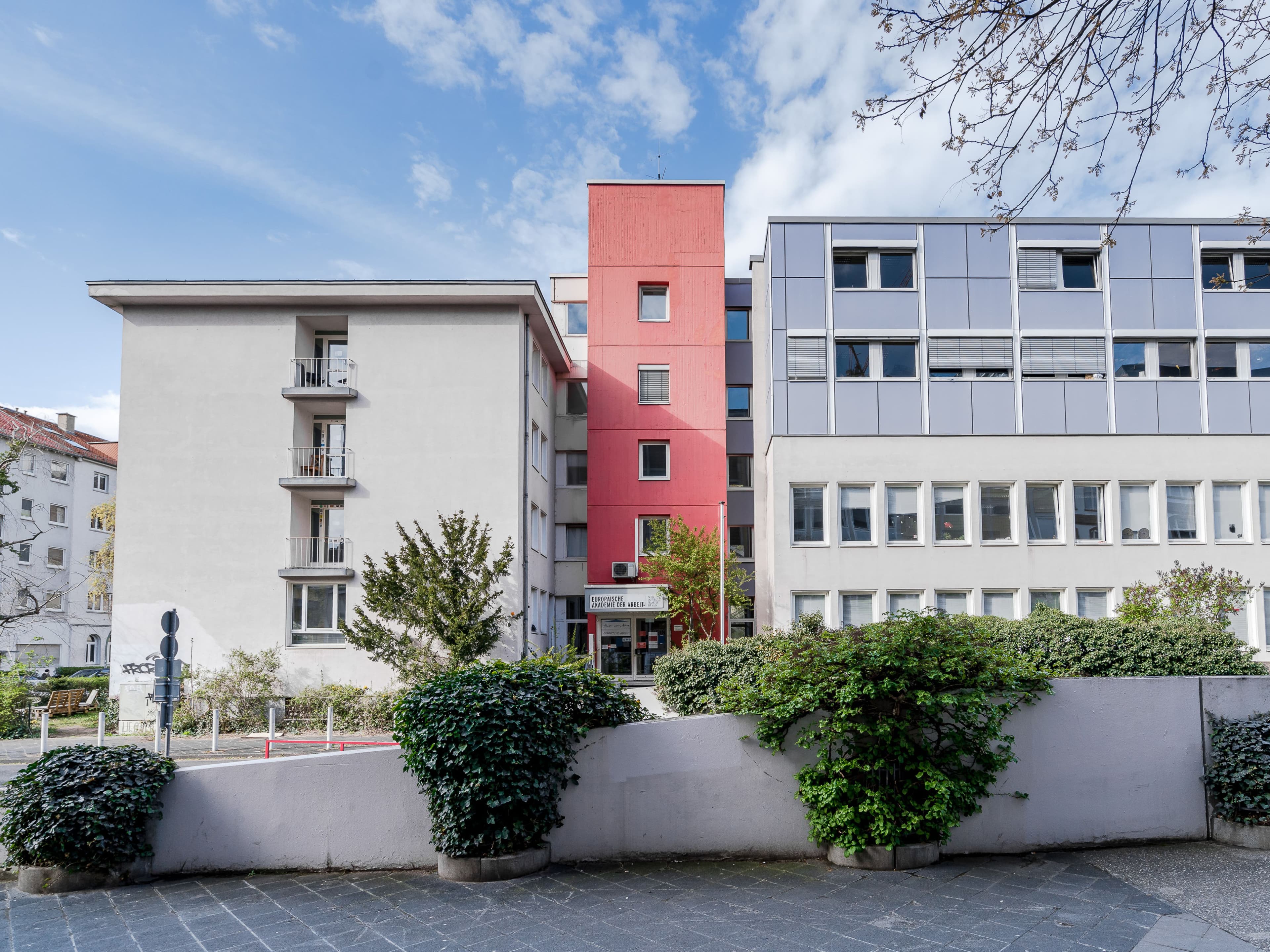 Zu sehen ist ein Gebäude von außen, welches aus verschiedenen Gebäudekomplexen zusammengesetzt ist.