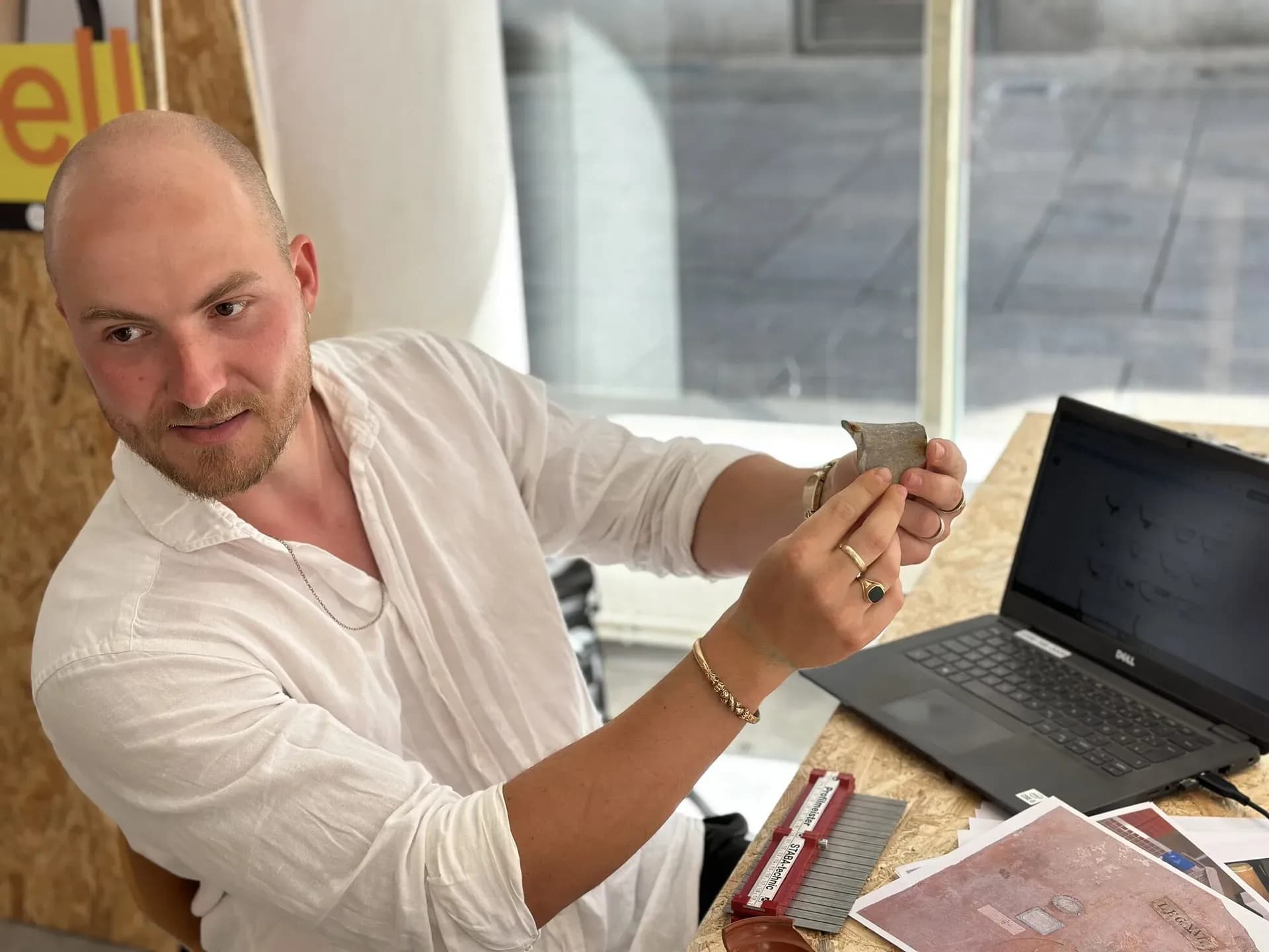 Ein Mann hält einen historischen Fund in der Hand und erklärt etwas