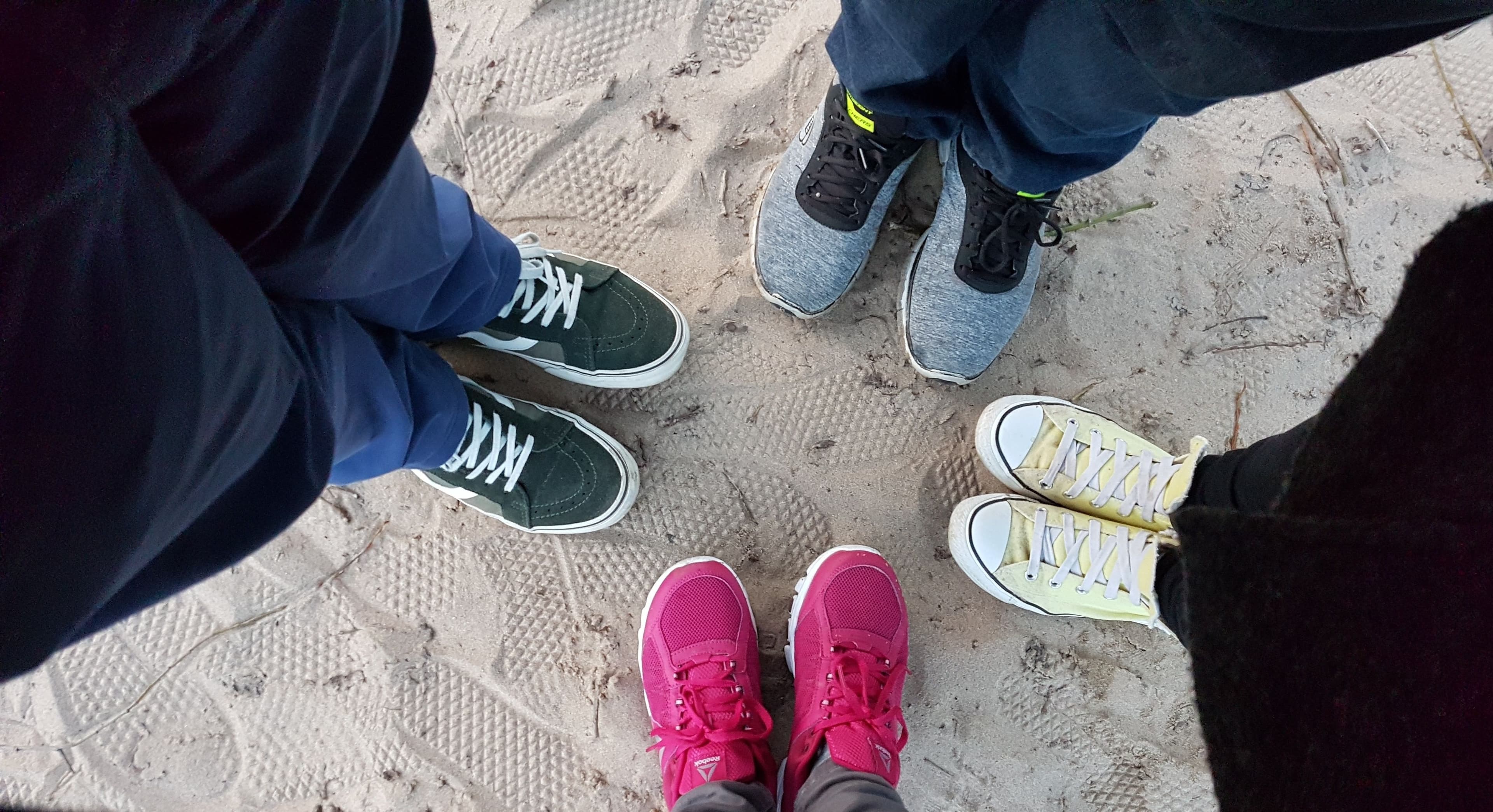 Vier Paar Füße stehen im Sand