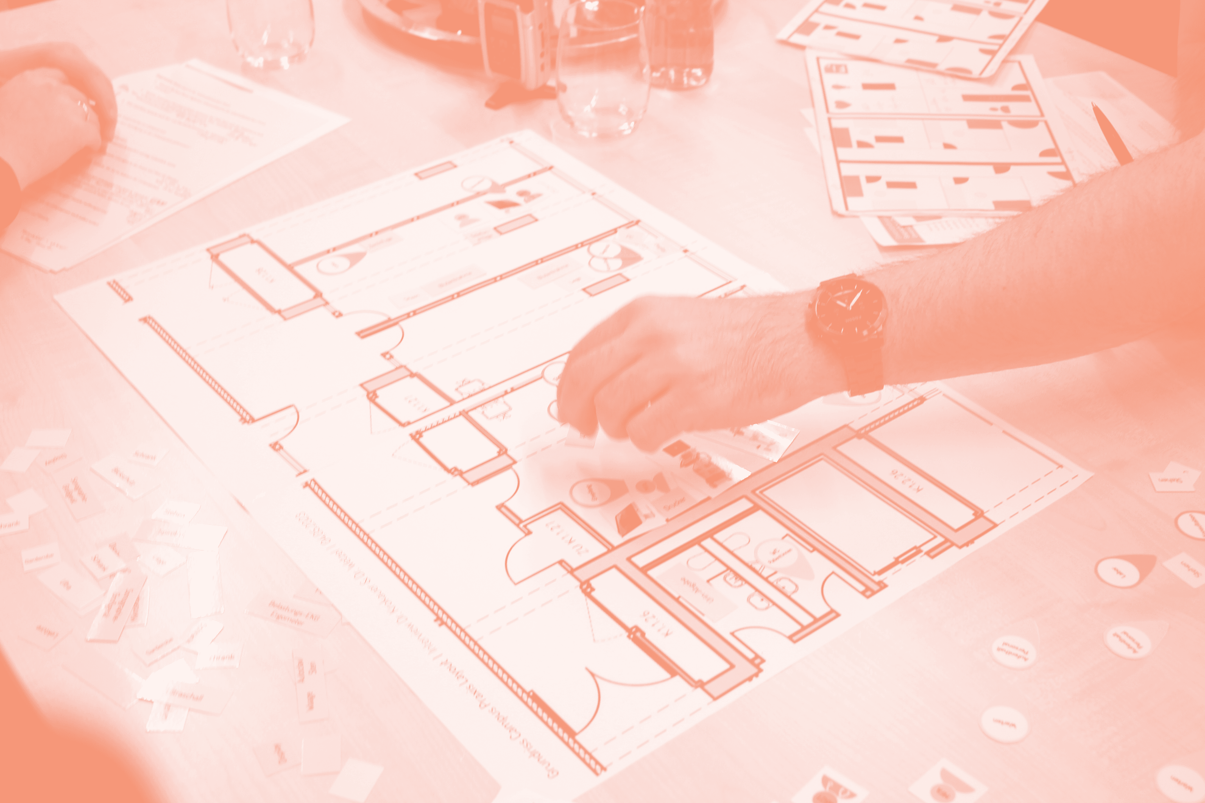 Eine Hand legt einen Gegenstand auf einen ausgedruckten Grundriss