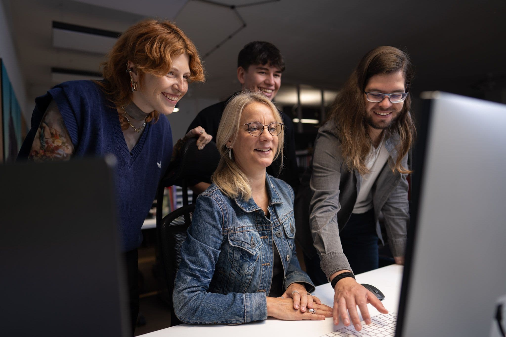 Vier Menschen schauen gemeinsam auf einen Computerbildschirm