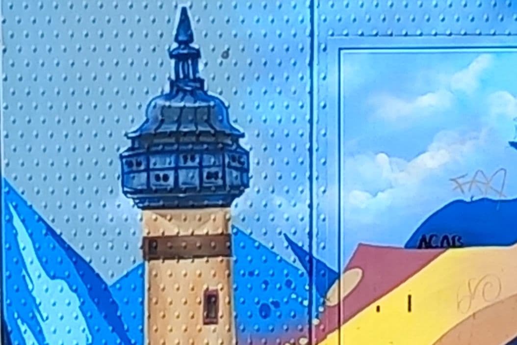 Ein Wandgemälde zeigt bunte Flächen und einen Turm