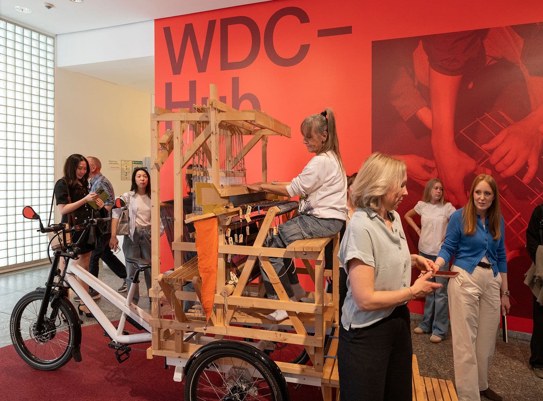 Eine Person auf dem mobilen Webstuhl der Ausstellung Loomcycle