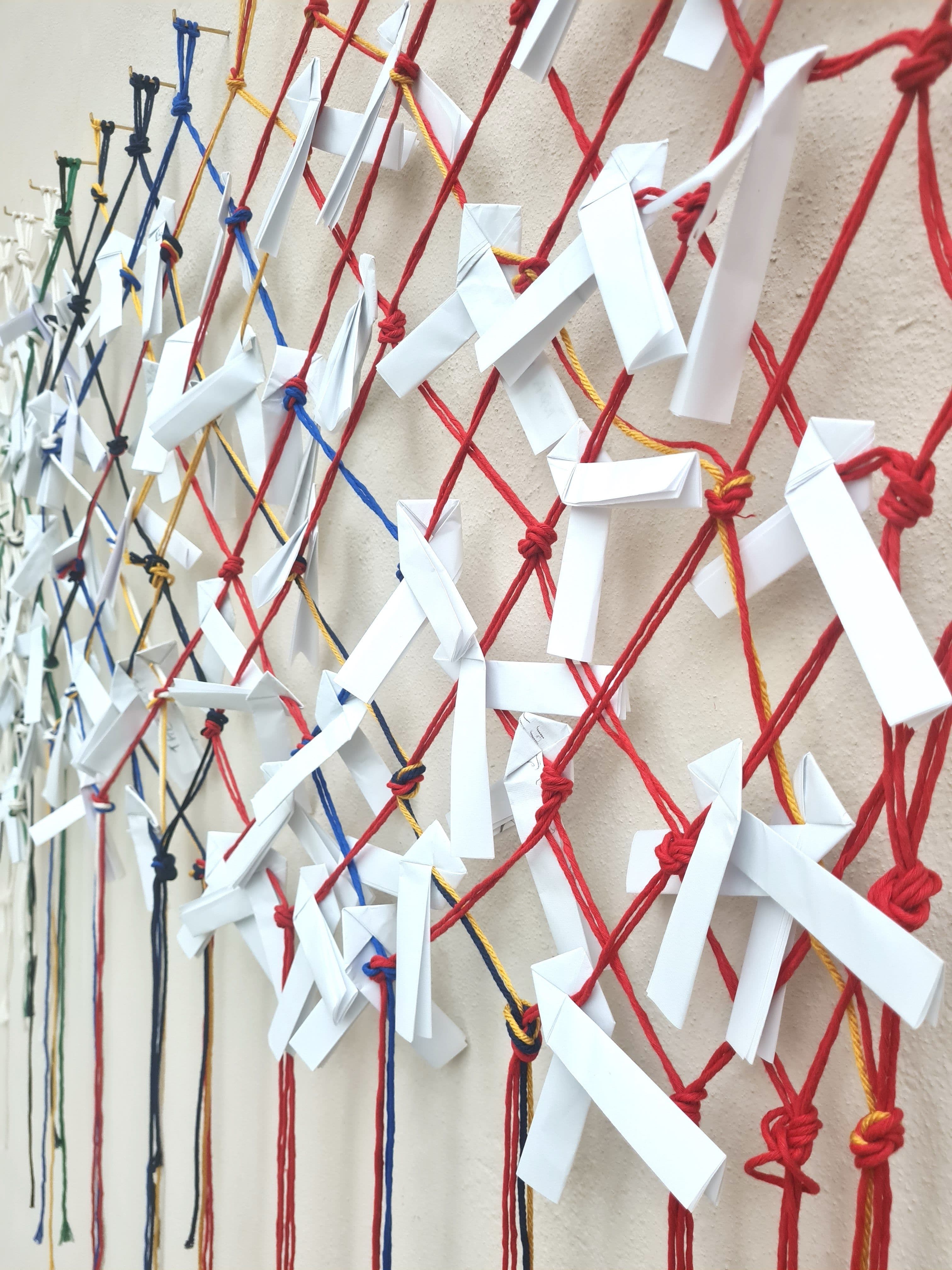 Ein Netz aus Schnüren und Papier hängt an einer Wand