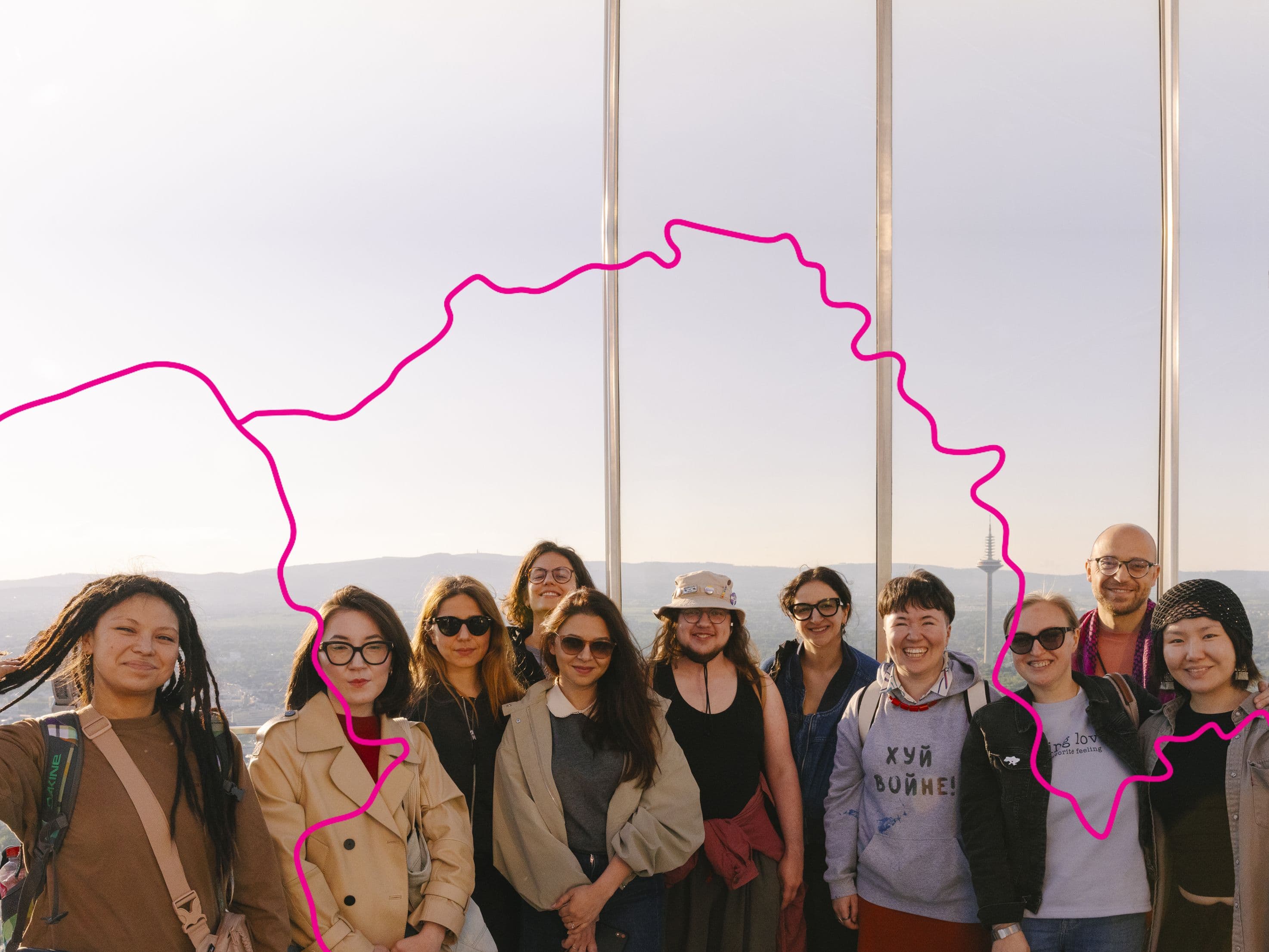 Eine Gruppe Menschen steht auf einem Aussichtspunkt und lacht in die Kamera